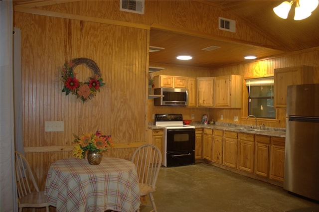 600 Jim Bowie Dr, Spicewood, TX 78669 - kitchen featuring appliances with stainless steel finishes, wood walls, finished concrete flooring, light countertops, and lofted ceiling