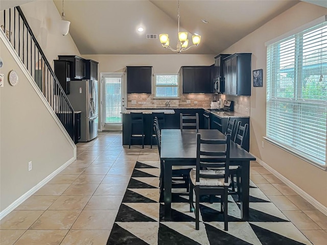 632 Schefer St, Leander, TX 78641 - kitchen featuring appliances with stainless steel finishes, a chandelier, lofted ceiling, dark cabinetry, and decorative backsplash