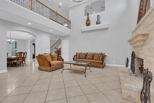 1130 Whispering Water, Spring Branch, TX 78070 - living area featuring light tile patterned floors, a high ceiling, arched walkways, stairs, and a fireplace with raised hearth