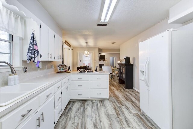 400 N Brazos St, Granger, TX 76530 - kitchen with white fridge with ice dispenser, white cabinetry, plenty of natural light, light countertops, and a textured ceiling