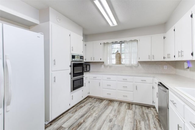 400 N Brazos St, Granger, TX 76530 - kitchen featuring freestanding refrigerator, dishwasher, light countertops, white cabinetry, and a textured ceiling