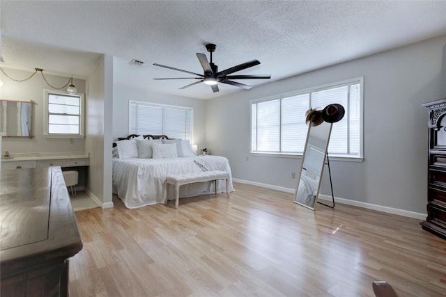 400 N Brazos St, Granger, TX 76530 - bedroom featuring multiple windows, a textured ceiling, light wood-style flooring, and a ceiling fan