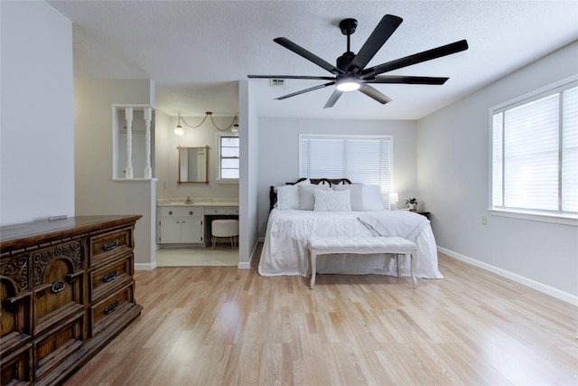 400 N Brazos St, Granger, TX 76530 - bedroom with light wood finished floors, ensuite bathroom, and ceiling fan