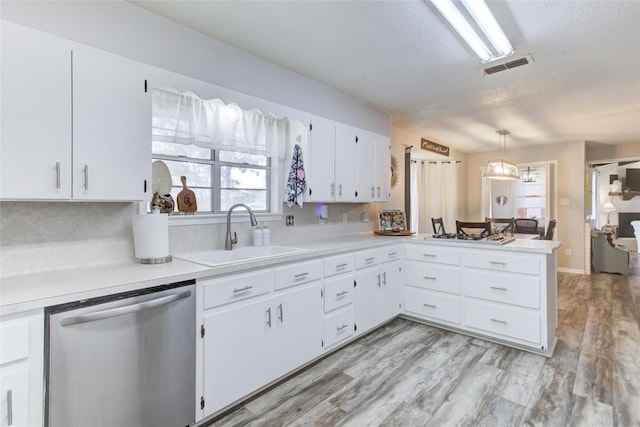 400 N Brazos St, Granger, TX 76530 - kitchen featuring dishwasher, light countertops, a textured ceiling, a peninsula, and white cabinetry