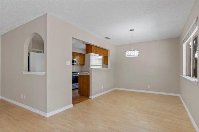 901 Pack Saddle Pass, Round Rock, TX 78681 - empty room with a textured ceiling, light wood-type flooring, a chandelier, and arched walkways