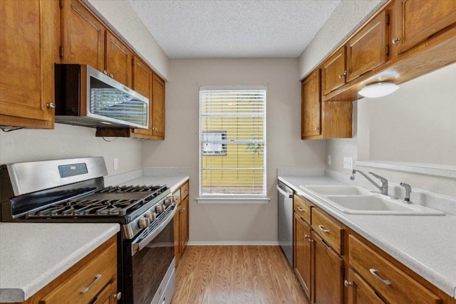 901 Pack Saddle Pass, Round Rock, TX 78681 - kitchen featuring appliances with stainless steel finishes, light wood finished floors, brown cabinetry, light countertops, and a textured ceiling