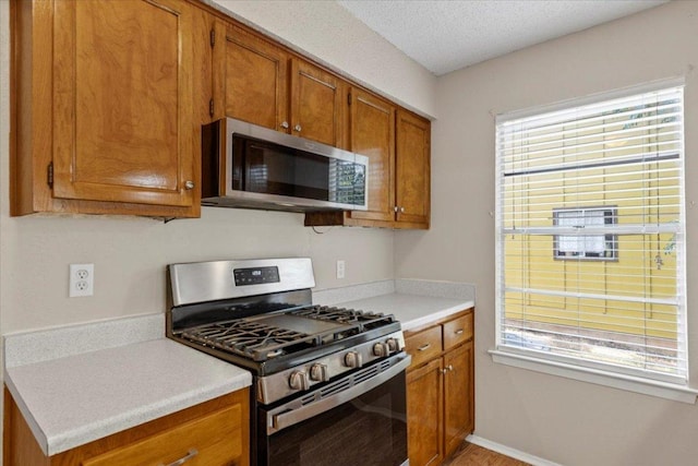 901 Pack Saddle Pass, Round Rock, TX 78681 - kitchen featuring stainless steel appliances, brown cabinets, light countertops, light wood-style floors, and a textured ceiling