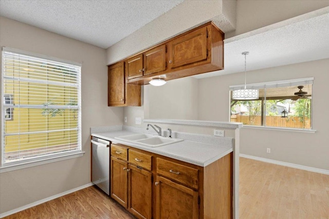 901 Pack Saddle Pass, Round Rock, TX 78681 - kitchen featuring stainless steel dishwasher, light wood finished floors, brown cabinetry, light countertops, and a textured ceiling