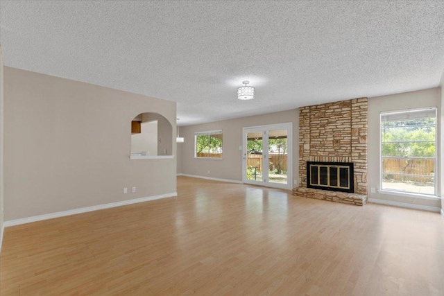901 Pack Saddle Pass, Round Rock, TX 78681 - unfurnished living room with light wood-style flooring, a textured ceiling, healthy amount of natural light, and a fireplace
