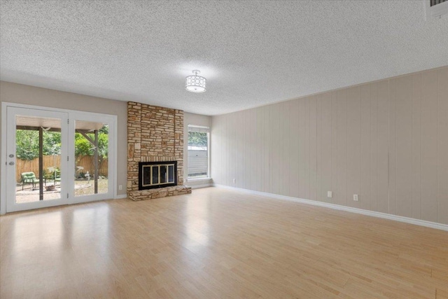 901 Pack Saddle Pass, Round Rock, TX 78681 - unfurnished living room featuring light wood-style flooring, a textured ceiling, and a fireplace