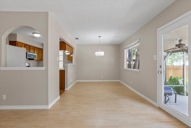 901 Pack Saddle Pass, Round Rock, TX 78681 - unfurnished dining area with light wood-style floors, arched walkways, a textured ceiling, and a ceiling fan