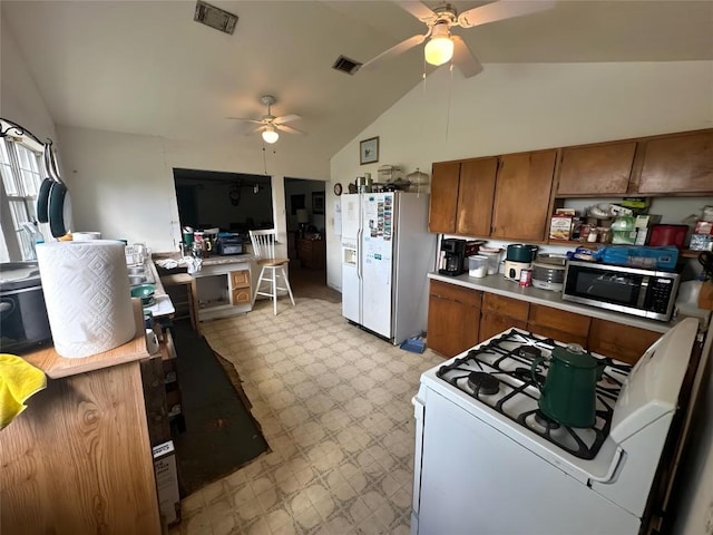 321 Douglas St, Lexington, TX 78947 - kitchen with white appliances, brown cabinets, a ceiling fan, vaulted ceiling, and light floors