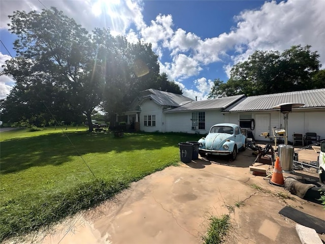 321 Douglas St, Lexington, TX 78947 - view of front of house featuring a front lawn, a metal roof, concrete driveway, and a patio area