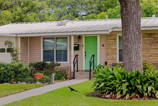 1314 Cloverleaf Dr, Austin, TX 78723 - view of front of property featuring a front lawn, a metal roof, stone siding, and an attached garage