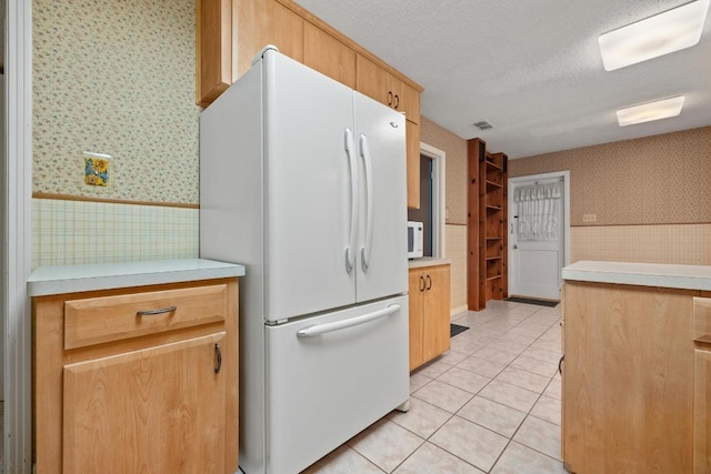 1314 Cloverleaf Dr, Austin, TX 78723 - kitchen with freestanding refrigerator, wallpapered walls, a wainscoted wall, light countertops, and light tile patterned floors