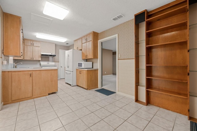 1314 Cloverleaf Dr, Austin, TX 78723 - kitchen with white appliances, wallpapered walls, light countertops, under cabinet range hood, and a peninsula