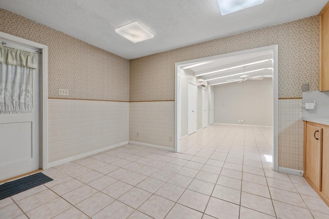 1314 Cloverleaf Dr, Austin, TX 78723 - spare room with wallpapered walls, wainscoting, a ceiling fan, light tile patterned floors, and a textured ceiling