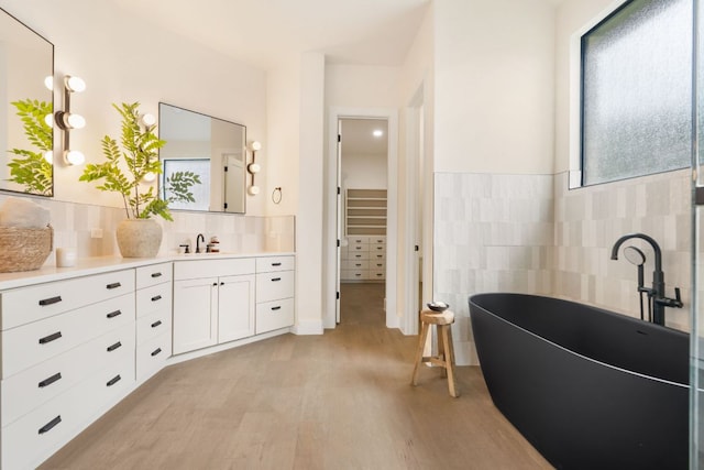12309 Carlsbad Dr, Austin, TX 78738 - full bathroom with tile walls, vanity, wood finished floors, a freestanding tub, and a walk in closet