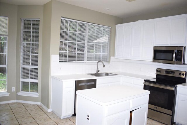 30007 Oakland Hills Dr, Georgetown, TX 78628 - kitchen with stainless steel appliances, tasteful backsplash, white cabinetry, light countertops, and a center island