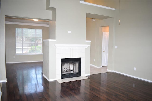 30007 Oakland Hills Dr, Georgetown, TX 78628 - unfurnished living room featuring wood finished floors, a tiled fireplace, and crown molding