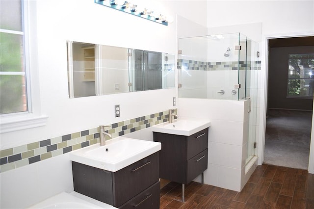 30007 Oakland Hills Dr, Georgetown, TX 78628 - bathroom with a shower stall, two vanities, wood finished floors, and decorative backsplash