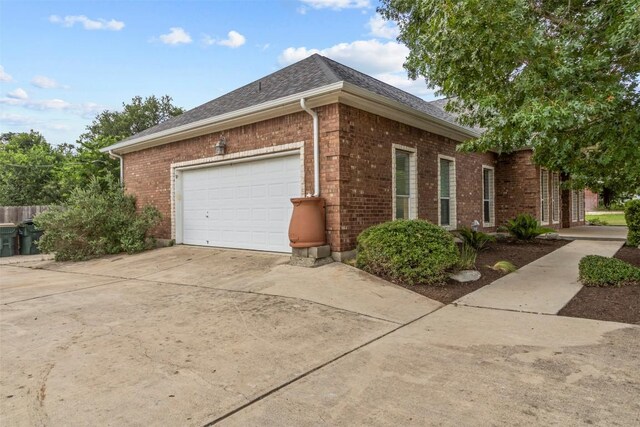 1205 Mountain View Dr, San Marcos, TX 78666 - view of property exterior featuring brick siding, driveway, a shingled roof, and an attached garage