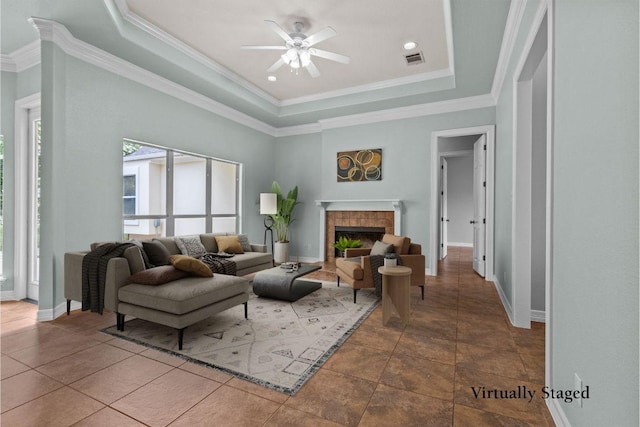 1205 Mountain View Dr, San Marcos, TX 78666 - living room featuring a raised ceiling, a ceiling fan, a tile fireplace, and ornamental molding