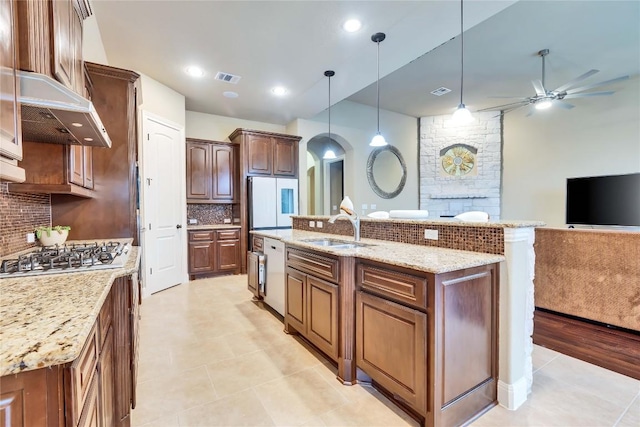 4108 Charbray Ct, Cedar Park, TX 78613 - kitchen with appliances with stainless steel finishes, a ceiling fan, decorative backsplash, arched walkways, and under cabinet range hood
