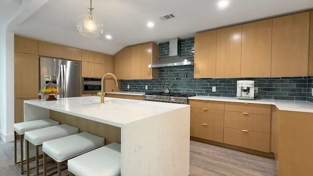 6709 Vine St, Austin, TX 78757 - kitchen featuring appliances with stainless steel finishes, wall chimney range hood, light wood-style floors, backsplash, and modern cabinets