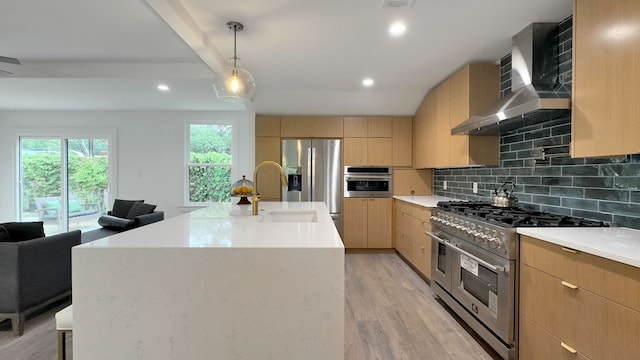 6709 Vine St, Austin, TX 78757 - kitchen featuring appliances with stainless steel finishes, wall chimney exhaust hood, light brown cabinets, modern cabinets, and tasteful backsplash