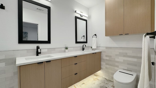 6709 Vine St, Austin, TX 78757 - bathroom with tile walls, double vanity, marble finish flooring, and a wainscoted wall