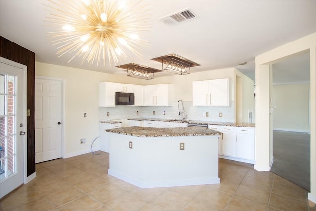 1112 Statler Bend Dr, Pflugerville, TX 78660 - kitchen featuring black microwave, a kitchen island, light stone counters, white cabinetry, and light tile patterned flooring