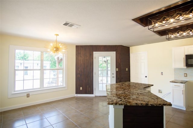 1112 Statler Bend Dr, Pflugerville, TX 78660 - kitchen featuring a chandelier, black microwave, dark stone counters, white cabinetry, and light tile patterned floors
