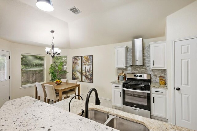 2519 Gate Ridge Dr, Austin, TX 78748 - kitchen featuring wall chimney range hood, stainless steel range with gas cooktop, lofted ceiling, white cabinets, and a chandelier