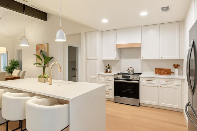 12001 Mossbrook Cv, Austin, TX 78750 - kitchen with stainless steel appliances, light wood-style flooring, white cabinetry, decorative light fixtures, and a kitchen breakfast bar