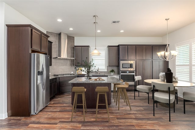 3805 Wales Ct Unit 611, Round Rock, TX 78681 - kitchen with appliances with stainless steel finishes, wall chimney range hood, dark brown cabinetry, decorative backsplash, and a chandelier
