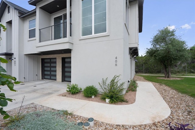 12001 Vista Parke Dr Unit 406, Austin, TX 78726 - view of side of property featuring board and batten siding, an attached garage, a balcony, and driveway
