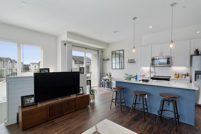 12001 Vista Parke Dr Unit 406, Austin, TX 78726 - kitchen with stainless steel microwave, refrigerator with ice dispenser, dark wood-type flooring, a kitchen breakfast bar, and recessed lighting