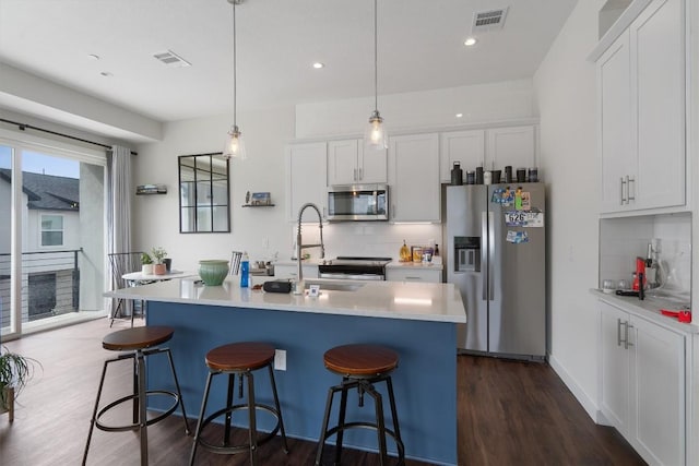 12001 Vista Parke Dr Unit 406, Austin, TX 78726 - kitchen featuring appliances with stainless steel finishes, tasteful backsplash, a kitchen bar, white cabinetry, and recessed lighting