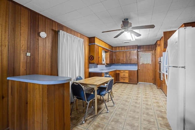 1213 Norbert St, Marlin, TX 76661 - kitchen featuring freestanding refrigerator, brown cabinetry, ceiling fan, wooden walls, and light floors