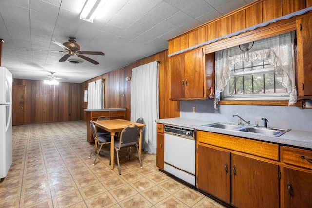 1213 Norbert St, Marlin, TX 76661 - kitchen with white appliances, light countertops, brown cabinetry, wooden walls, and a ceiling fan