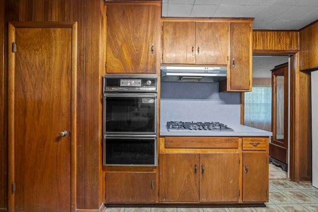 1213 Norbert St, Marlin, TX 76661 - kitchen featuring under cabinet range hood, stainless steel gas stovetop, light countertops, and brown cabinetry
