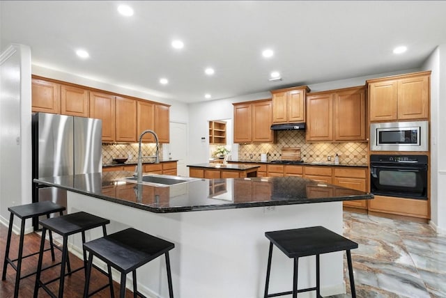 5704 Keli Ct, Austin, TX 78735 - kitchen featuring appliances with stainless steel finishes, a kitchen island with sink, a kitchen breakfast bar, decorative backsplash, and recessed lighting