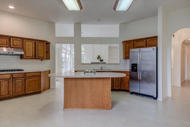 6604 Donner Cv, Austin, TX 78749 - kitchen with stainless steel fridge, under cabinet range hood, brown cabinetry, light countertops, and recessed lighting