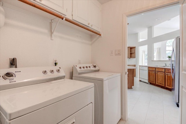 6604 Donner Cv, Austin, TX 78749 - laundry room featuring cabinet space, washing machine and clothes dryer, and light tile patterned flooring