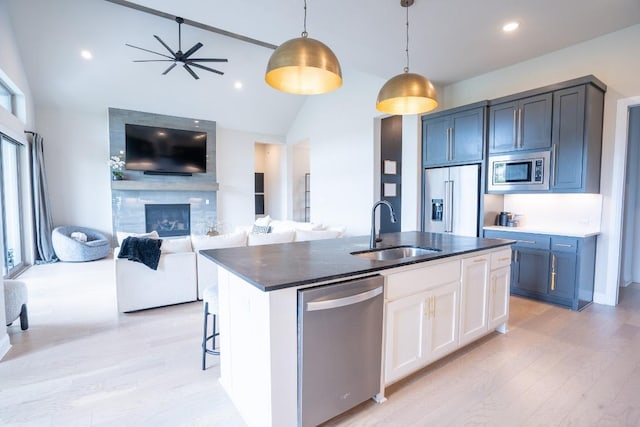2220 Normandy Vw, Leander, TX 78641 - kitchen with stainless steel appliances, open floor plan, dark countertops, light wood-style flooring, and a fireplace