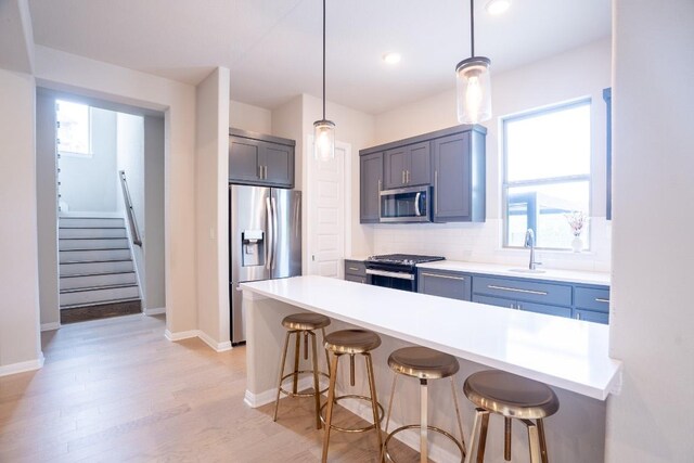 2220 Normandy Vw, Leander, TX 78641 - kitchen with stainless steel appliances, a kitchen breakfast bar, light wood-style flooring, decorative backsplash, and hanging light fixtures