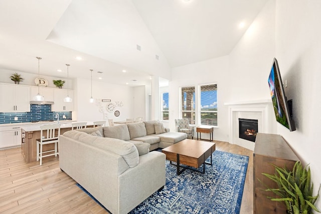 1535 Terrys Gate, New Braunfels, TX 78132 - living room featuring a glass covered fireplace, light wood-type flooring, high vaulted ceiling, and recessed lighting