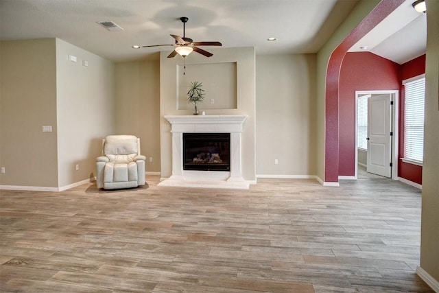 285 Chisholm Trl, Bastrop, TX 78602 - unfurnished living room featuring wood finished floors, ceiling fan, arched walkways, a glass covered fireplace, and recessed lighting