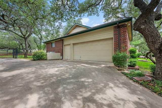125 Long Wood Ave, Lakeway, TX 78734 - view of side of property with brick siding, driveway, and an attached garage